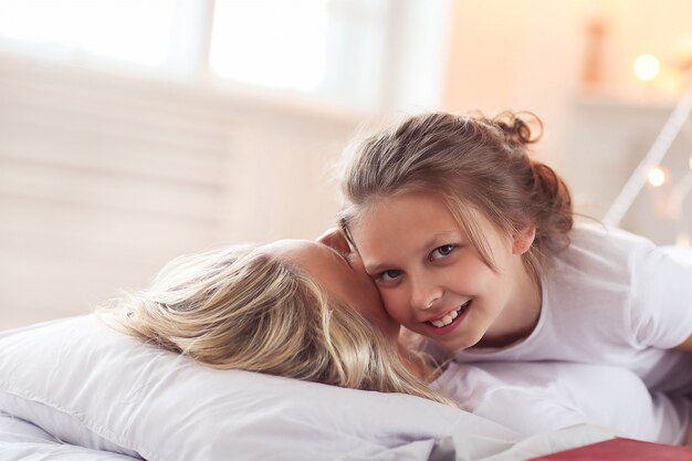 Family scene. Happy mother and daughter in a bed