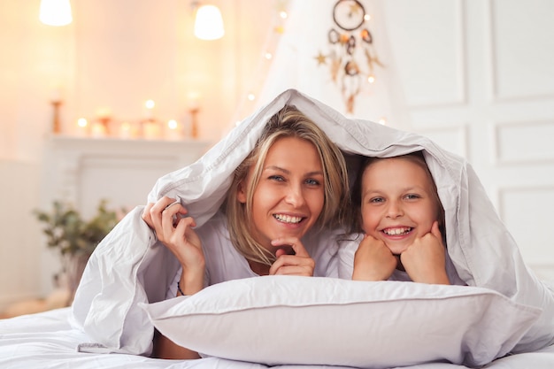 Family scene. Happy mother and daughter in a bed