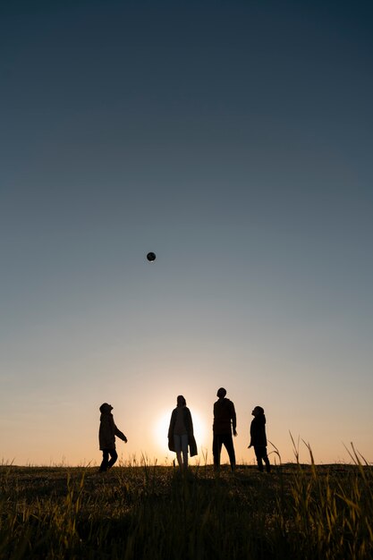 夕日のフルショットを楽しんでいる家族のシルエット