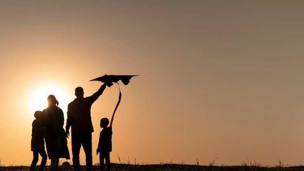 Siluette della famiglia che si divertono al tramonto a tutto campo