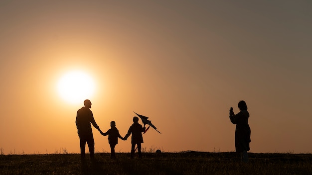 Foto gratuita siluette della famiglia che si divertono al tramonto a tutto campo