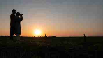 Foto gratuita siluette della famiglia che si divertono al tramonto a tutto campo