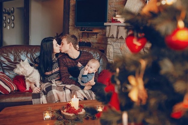 Family sitting on couch with christmas tree out of focus in front