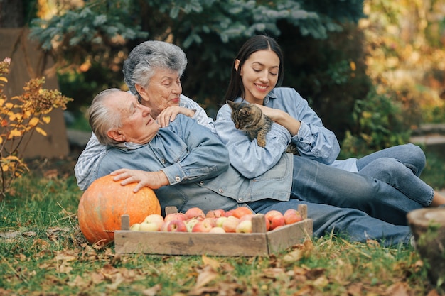 Семья сидит в саду с яблоками и тыквой