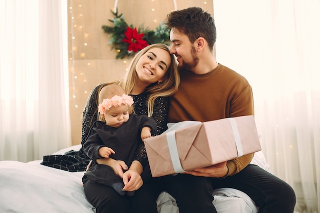 Family sitting at home on a bed with presents