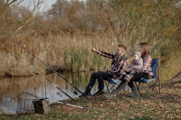 朝の釣りで川の近くに座っている家族