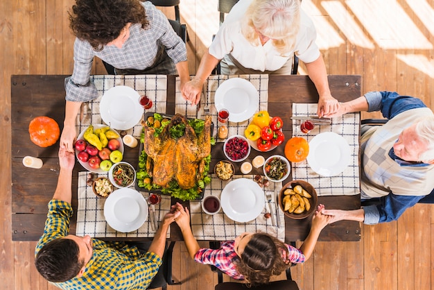 Family sitting at table with holding hands Premium Photo