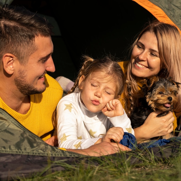 Family sitting in tent with their dog close-up