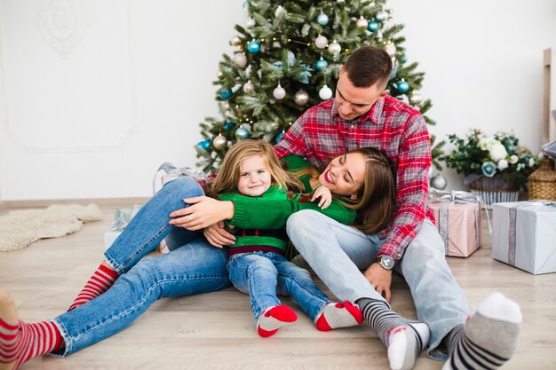 Family sitting together in front of christmas tree