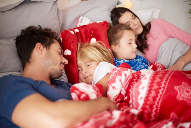 Family sleeping in bed together