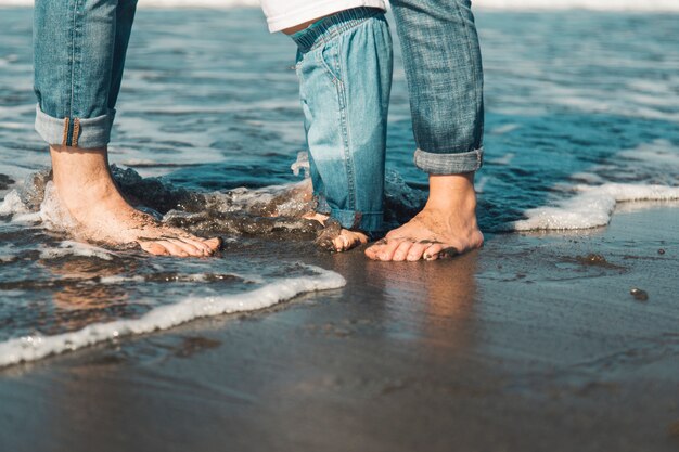 Family standing barefoot on wet sand at beach