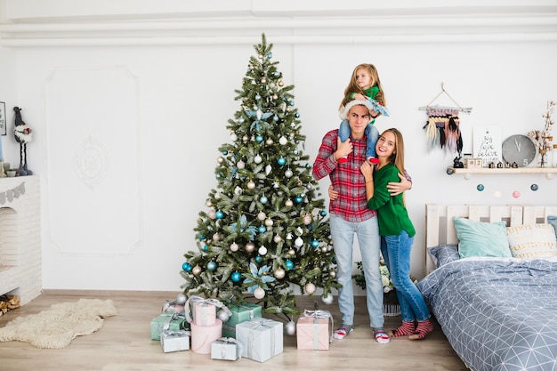 Family standing next to christmas tree