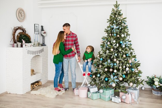 Family standing next to christmas tree