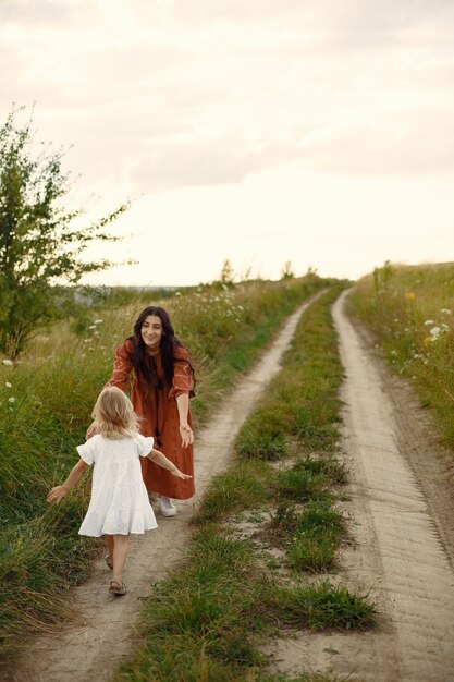 Семья в летнем поле. Мать в коричневом платье. Милая маленькая девочка.