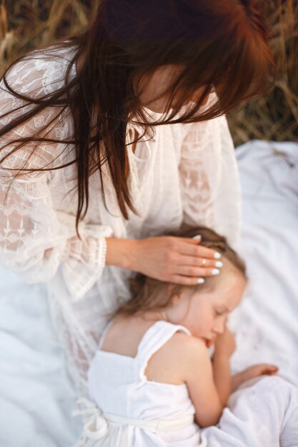 Family in a summer field. Sensual photo. Cute little girl. Woman in a white dress.