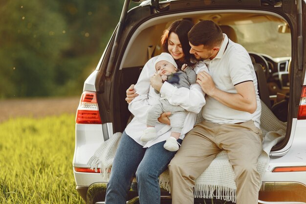 Family in a summer forest by the open trunk