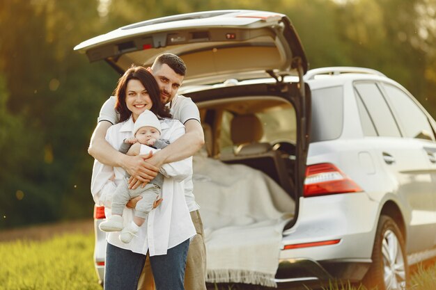 Family in a summer forest by the open trunk