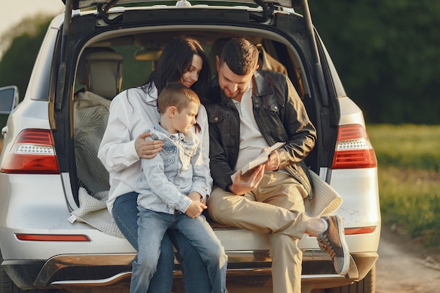 Family in a summer forest by the open trunk