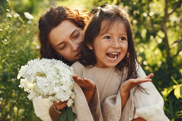 夏の庭で家族。官能的な写真。かわいい女の子。花束を持つ女性。