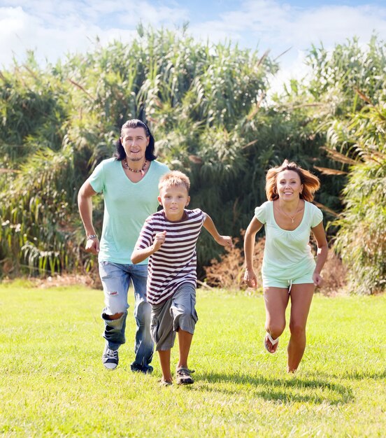 Family of three running on grass