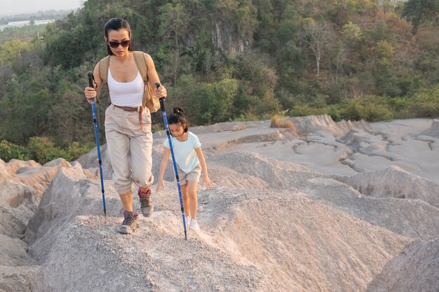 家族旅行-山の景色を眺めるバックパックを持ったハイカー、日中は母親と子供。