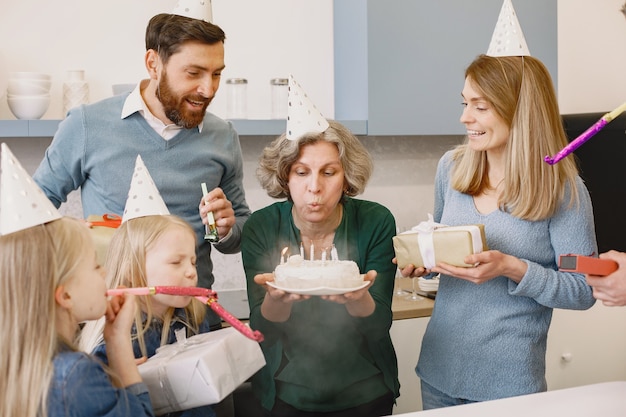 Семья и две дочери празднуют день рождения бабушки Старушка задувает свечи