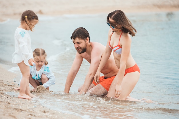Семейный отдых родителей и детей на берегу моря летний день
