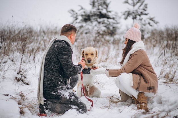 Семья гуляет в зимнем парке со своей собакой