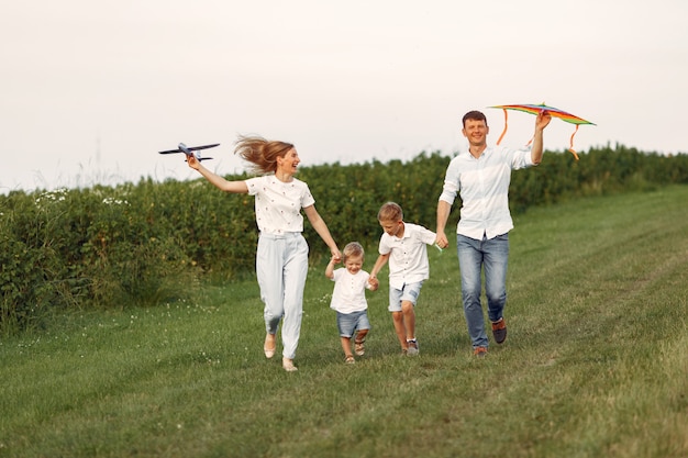 家族がフィールドを散歩し、おもちゃの飛行機で遊んで