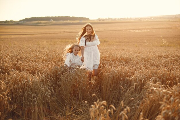 Family in a wheat field. Woman in a white dress. Girl with straw hat.