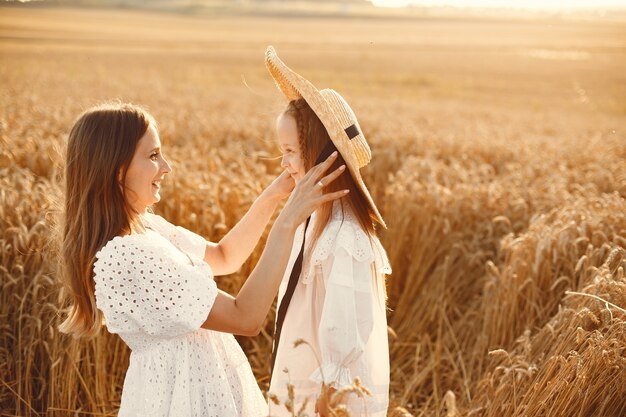 Family in a wheat field. Woman in a white dress. Girl with straw hat.