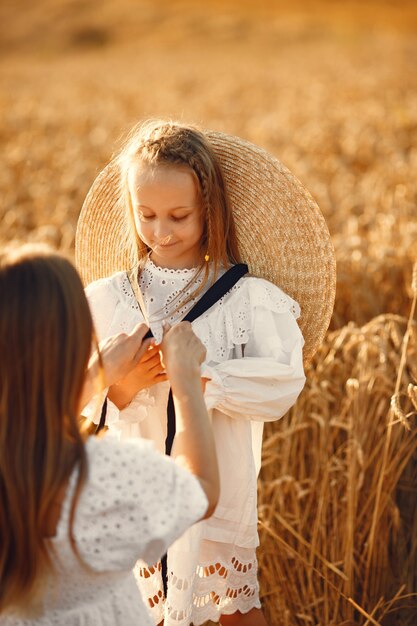 Family in a wheat field. Woman in a white dress. Girl with straw hat.