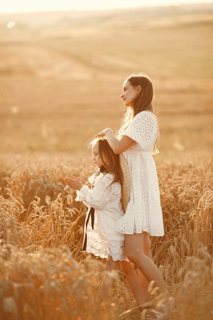Family in a wheat field. Woman in a white dress. Girl with straw hat.
