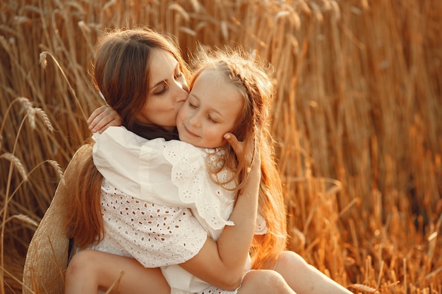 Family in a wheat field. Woman in a white dress. Girl with straw hat.