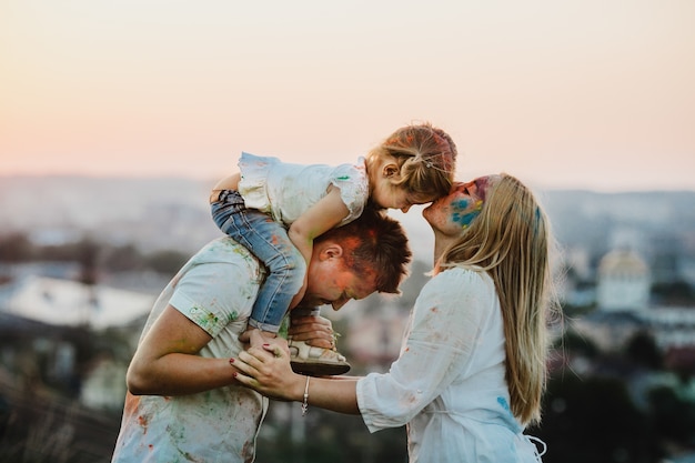 La famiglia in camicie bianche ricoperte di diverse pitture si trova all'esterno la sera