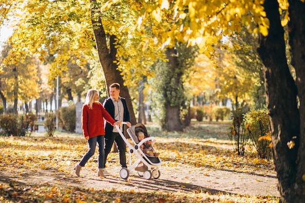 Family with baby daugher in a baby carriage walking an autumn park