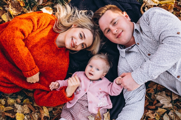 Family with baby daugher lying on leaves in park
