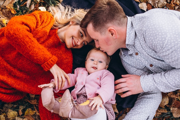 Family with baby daugher lying on leaves in park