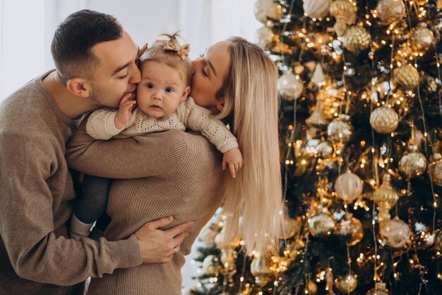 Family with baby daughter by the Christmas tree