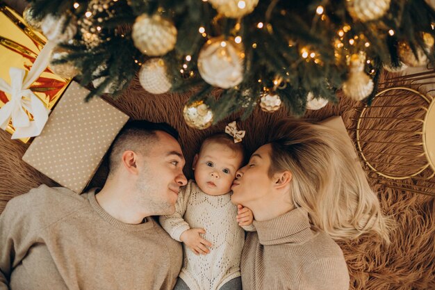 クリスマスツリーのそばの赤ん坊の娘と家族