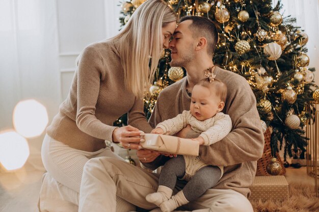 Family with baby daughter by the Christmas tree