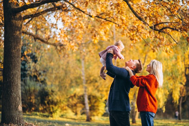 Семья с маленькой дочкой гуляет в осеннем парке