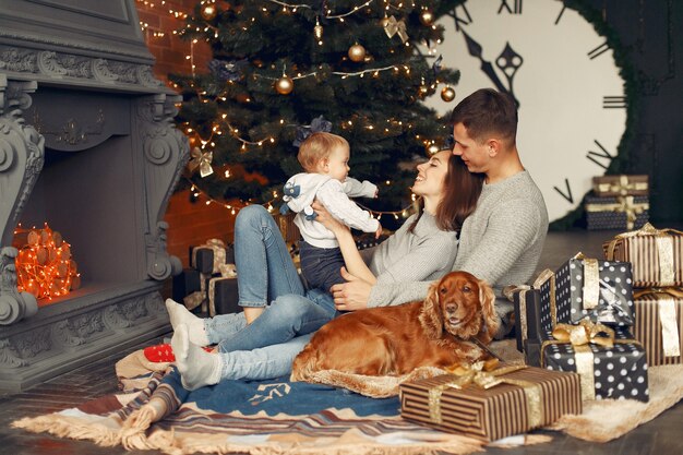 Family with cute dog at home near christmas tree