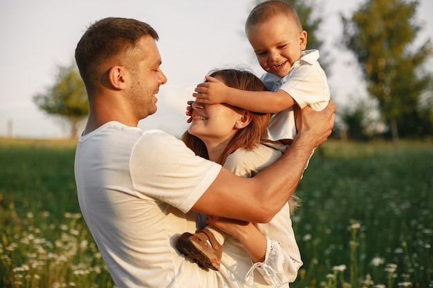 Foto gratuita famiglia con bambino piccolo carino. padre con una maglietta bianca. sfondo tramonto.