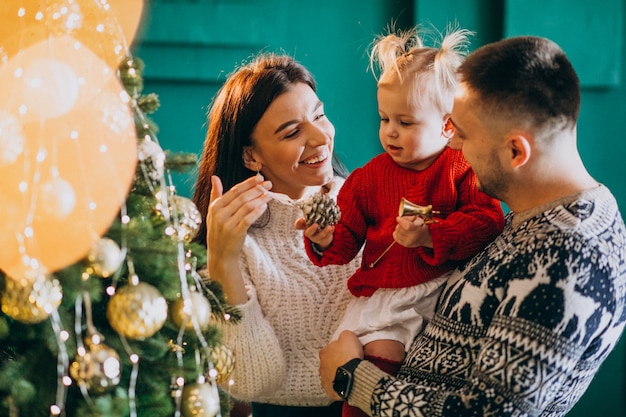 Foto gratuita la famiglia con la piccola figlia che appende gioca sull'albero di natale