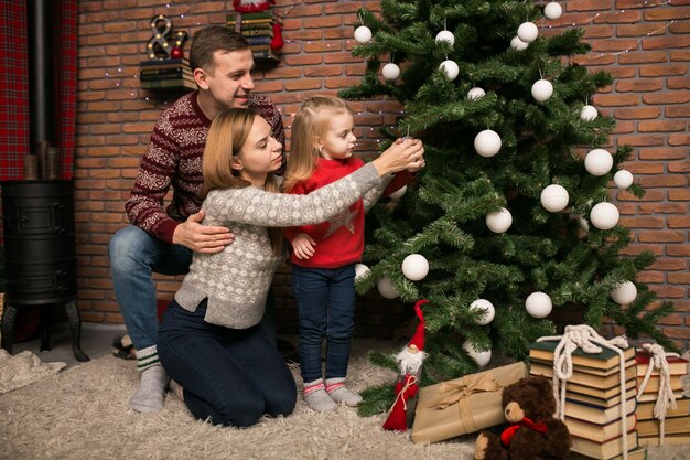 Family with little daughter hanging toys on a Christmas tree