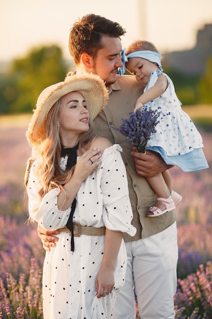Family with little daughter on lavender field. Beautiful woman and cute baby playing in meadow field. Family holiday in summer day.