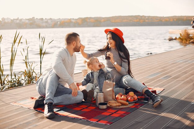 Family with little daughter sitting near water in a autumn park