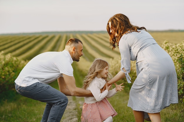 Family with little daughter spending time together in sunny field