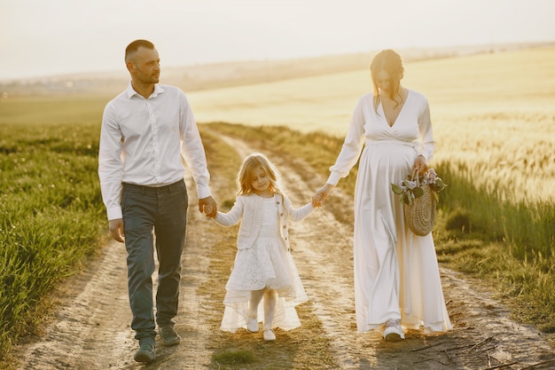 Family with little daughter spending time together in sunny field